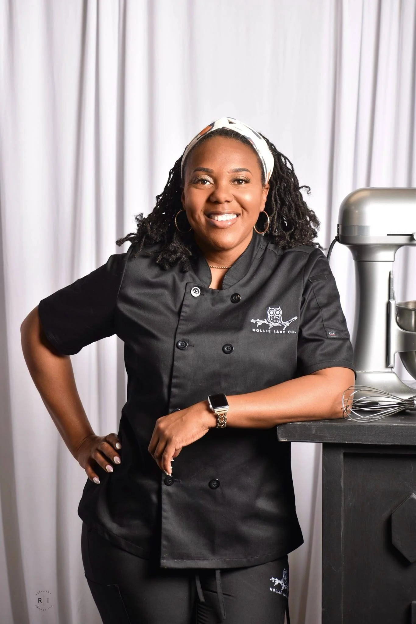 Mollie Jane Co. owner Sandra Plainer-Molden wearing a black baker’s coat beside a commercial mixer